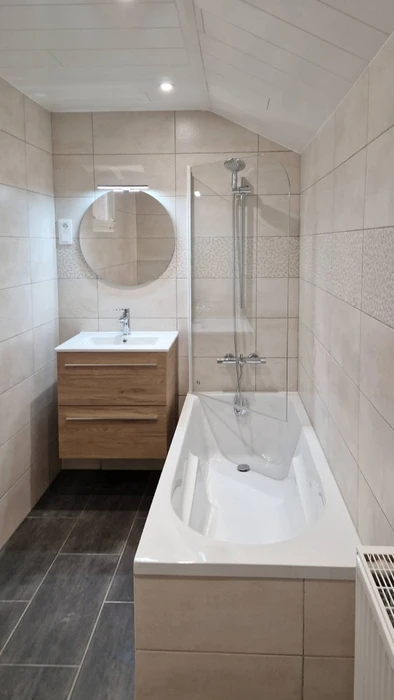 Salle de bain rénovée avec baignoire rectangulaire encastrée et paroi de douche en verre trempé sur rail chromé