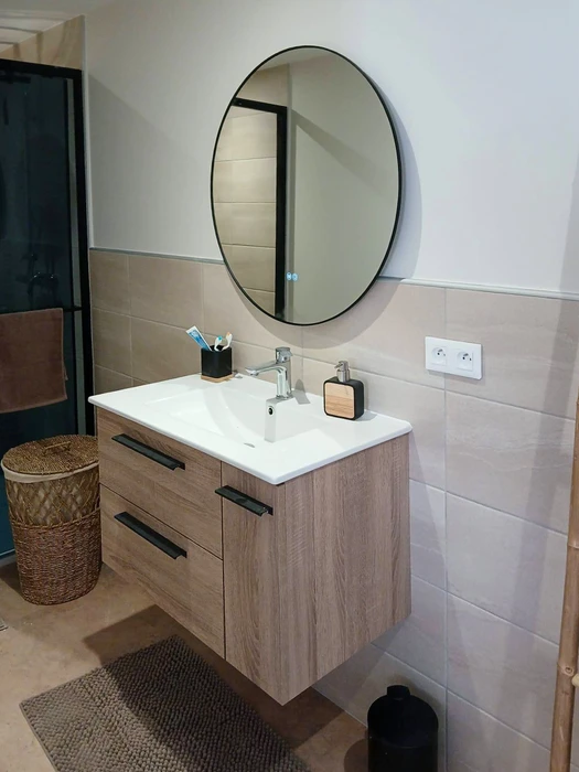 Salle de bain moderne avec meuble vasque suspendu en bois clair, plan vasque céramique blanc, robinetterie chromée monotrou