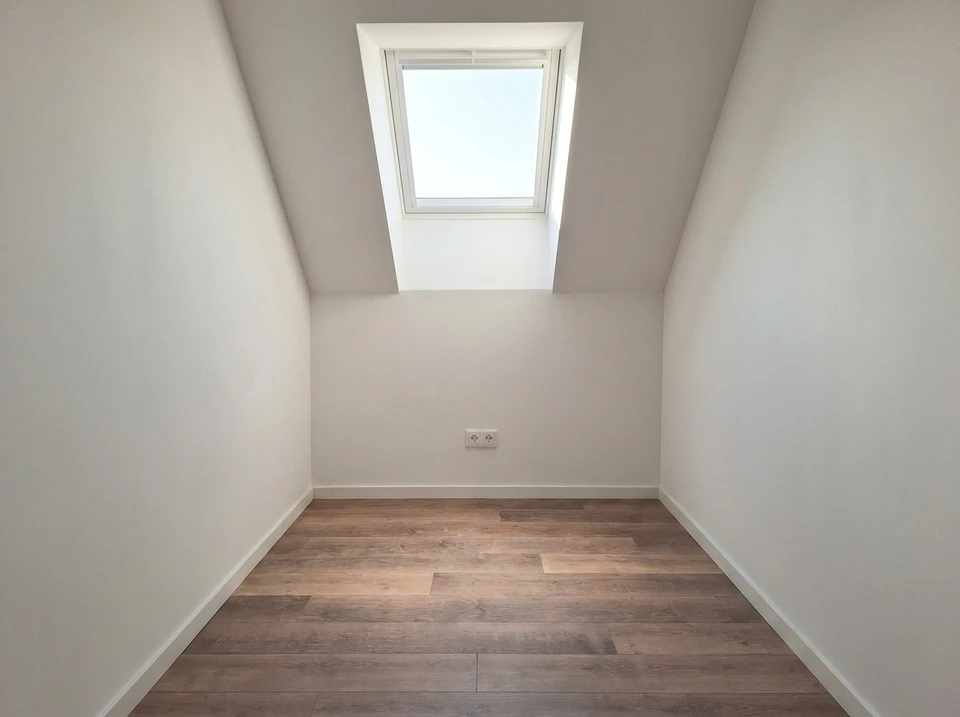 Photographie réaliste d'un chantier de rénovation intérieure avec plusieurs artisans travaillant simultanément : un carreleur posant du carrelage au sol, un électricien installant des éléments électriques, un peintre appliquant de la peinture murale, et un plombier travaillant sur les installations, tous dans le même espace résidentiel en cours de transformation. La scène doit montrer clairement la collaboration et la diversité des métiers présents sur le chantier.