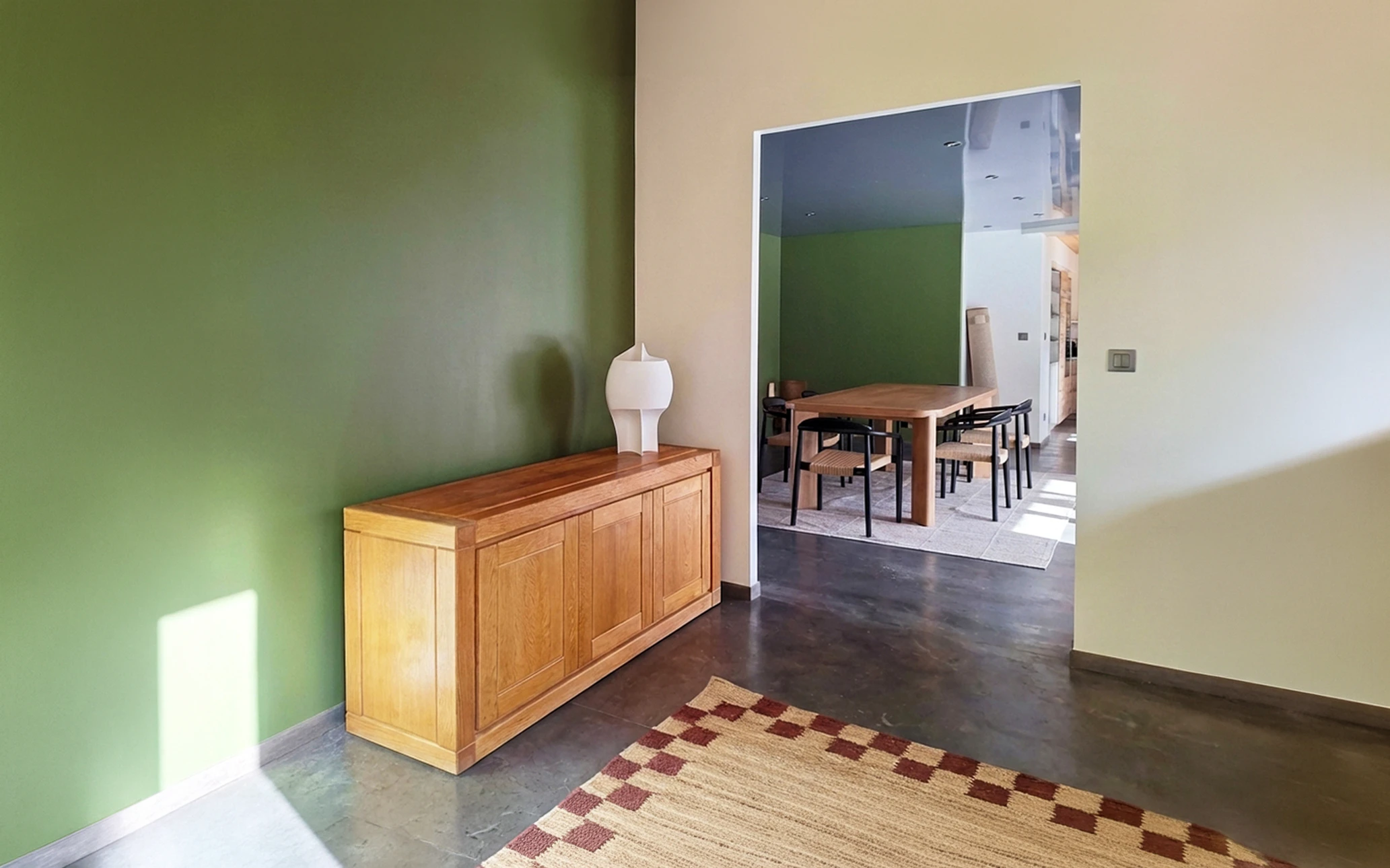 Photographie d'un intérieur résidentiel en cours de rénovation complète montrant plusieurs corps de métier en action simultanée : un artisan menuisier/carreleur travaillant sur des revêtements muraux, des éléments de construction ou d'aménagement visibles dans la pièce, avec des outils professionnels et matériaux de rénovation. La scène doit transmettre une dynamique de chantier professionnel et contrôlé, avec une pièce partiellement transformée montrant la progression d'une rénovation intérieure complète. Éclairage naturel, qualité photographique professionnelle. Aucun texte ni logo visible.