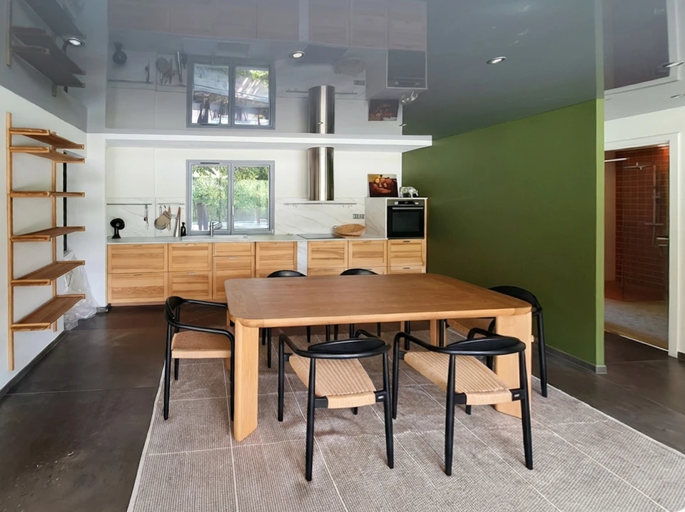 Professionnel en tenue professionnelle (costume ou chemise) effectuant un rendez-vous de consultation avec un client dans une cuisine en rénovation. Le professionnel prend des notes ou montre des plans sur un document, illustrant le rôle de coordinateur et d'interlocuteur unique du projet. La scène se déroule dans une cuisine en chantier où l'on voit des éléments de rénovation (outils, matériaux partiellement installés) en arrière-plan, symbolisant l'ensemble des travaux pilotés par cette seule personne.