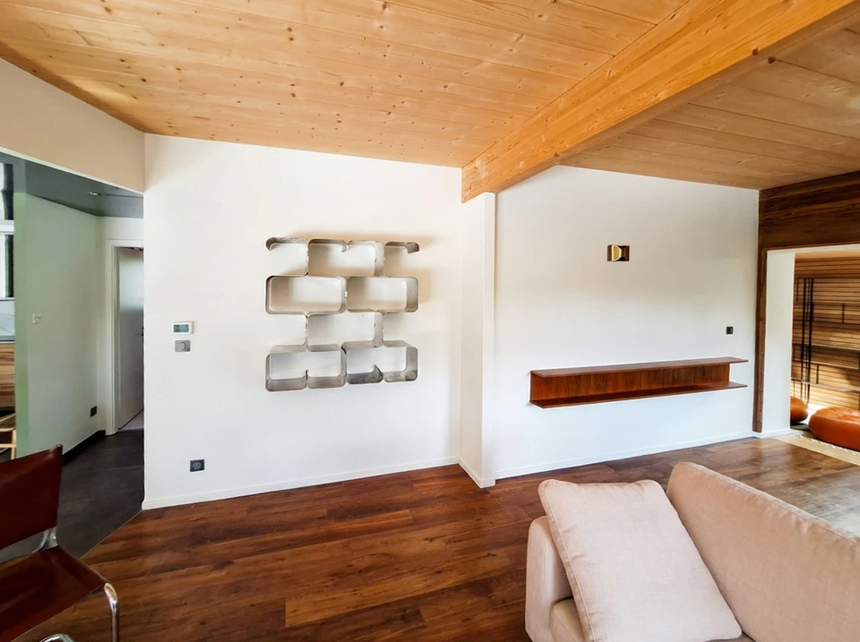 Mobilier élégant vintage dans un intérieur spacieux et plat avec canapé beige, chaises et affiches au mur